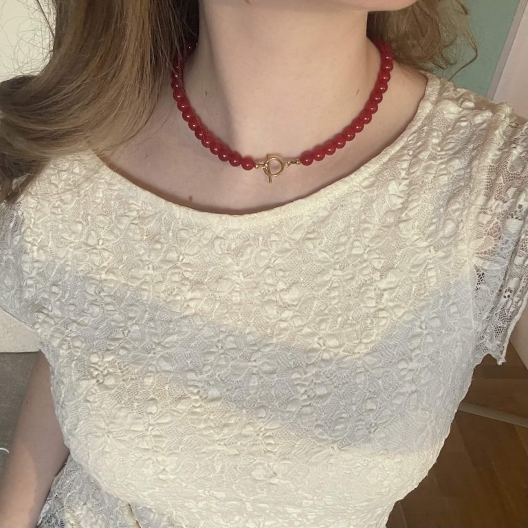 Modellbild på ett rött pärlhalsband med guldigt lås